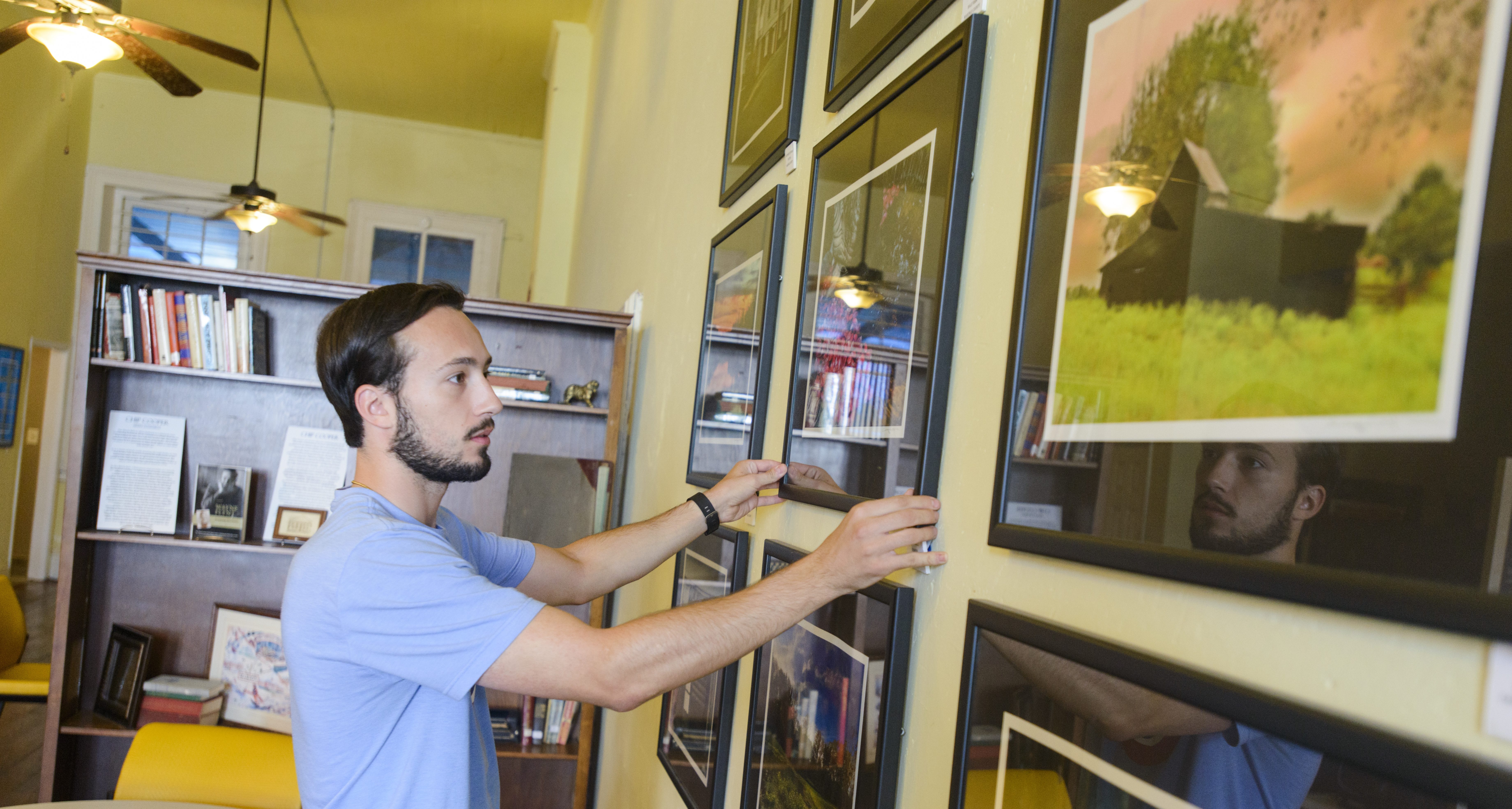 Story Image - Male student hanging photographs.