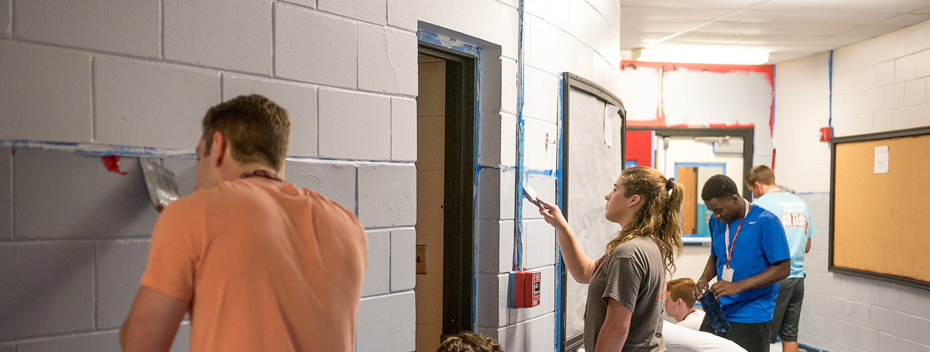 Story Image - Students painting an elementary school's walls to help out