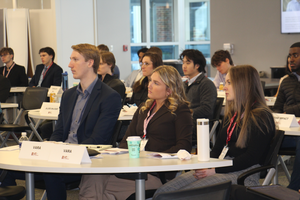 Three students sit at a table and look toward the left.