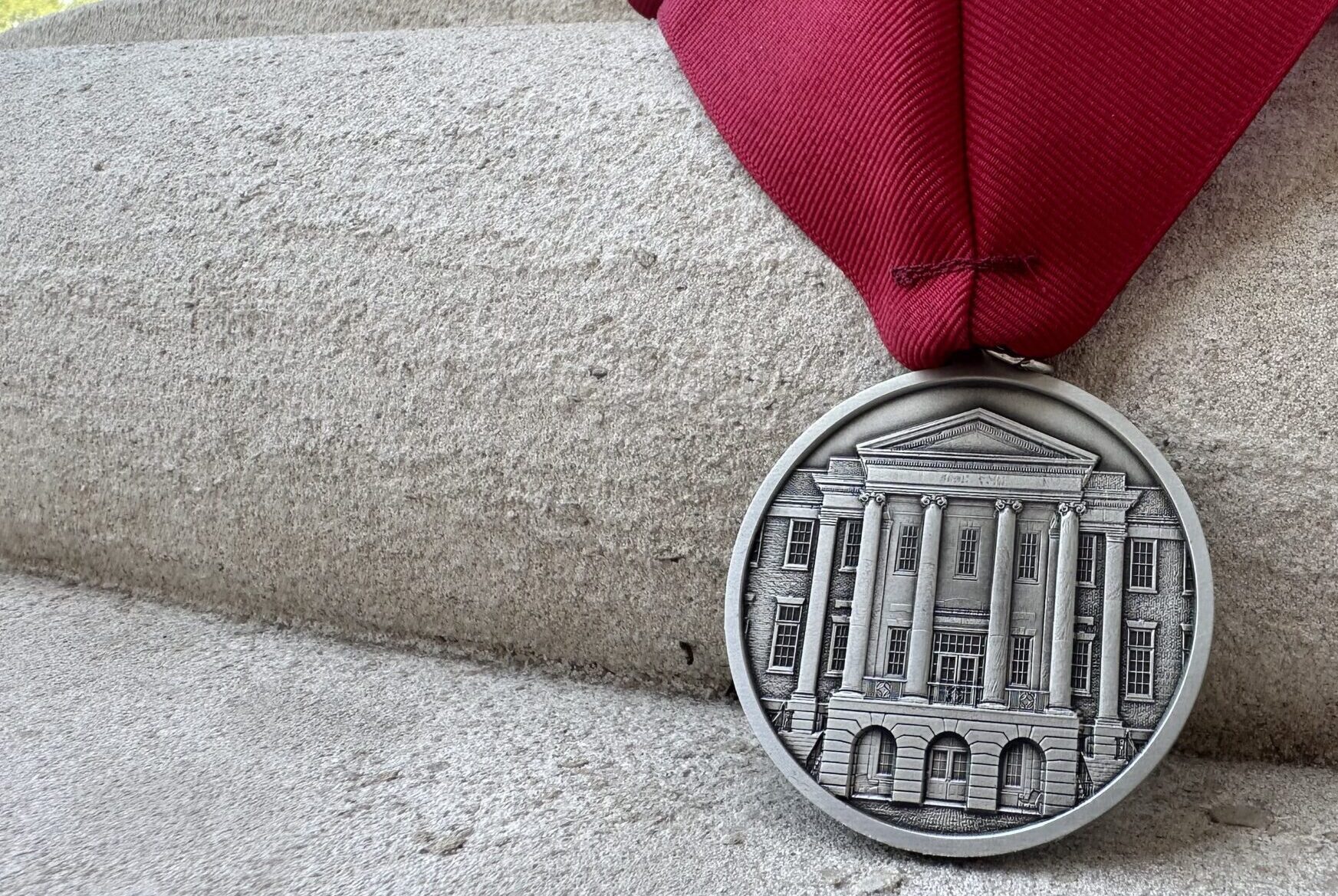 A medallion with Honors Hall engraved and with a crimson ribbon.