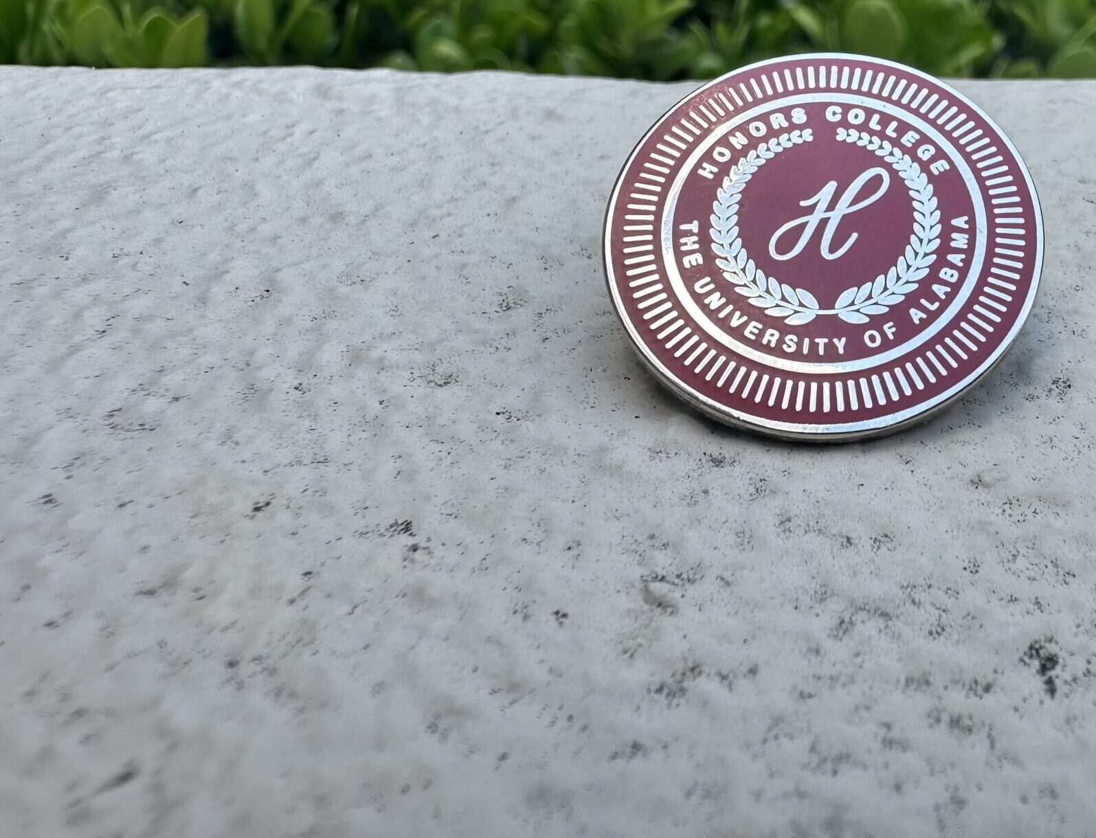 A crimson pin with the UA Honors College seal.