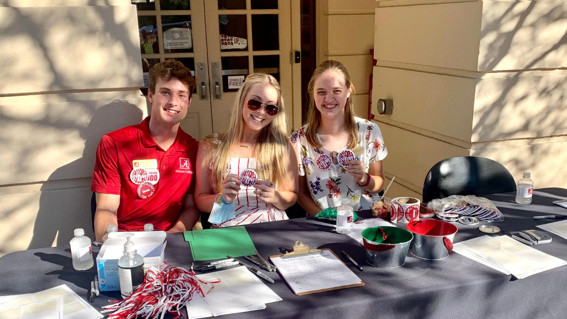 Three students smile and pose with buttons that read, "Honors College."