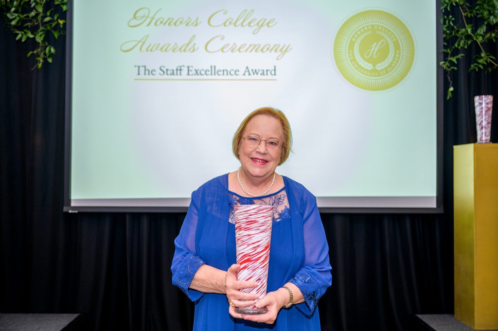Jane Batson smiles with her award, a crimson and white glass vase.