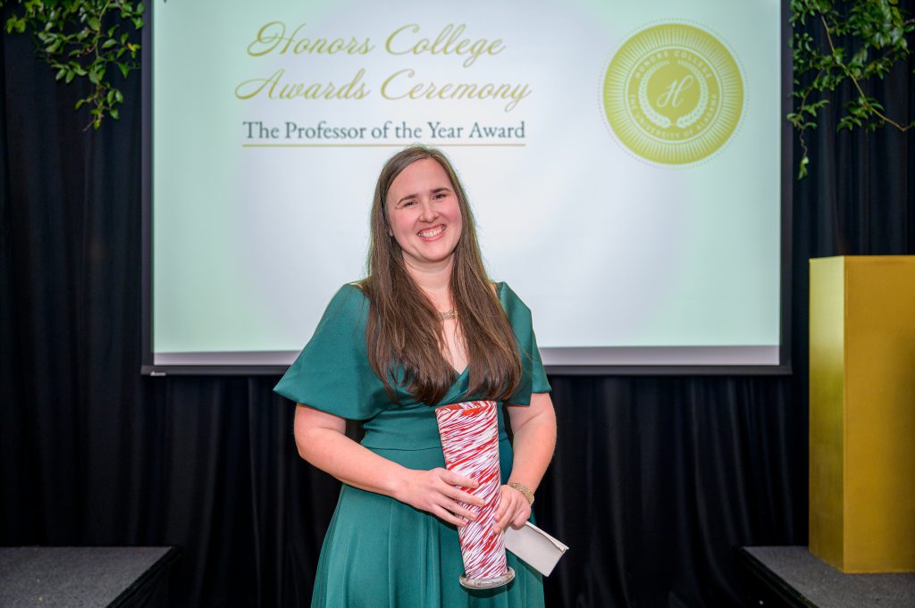 Dr. Anne Franklin Lamar smiles with her award, a crimson and white glass vase.